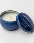 Apotheke earl grey bitters mini candle is featured in round dark blue container using white lettering on a white background.
