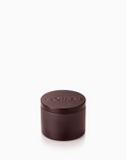 A small cylindrical dark brown apothecary jar with a matching lid, featuring the brand name 'APOTHEKE' embossed on top, set against a plain white background.