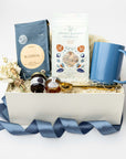 Gift basket with a blue mug, tea bags, and other items on a white background