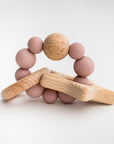 Blush star silicone and wood teether featured in image with wooden star, round wood circle attached by a round circle made of 9 round pink silicone balls and one wooden round ball.