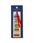 This image displays a Rifle Paper Co. book club bookmark featuring a stack of colorful, illustrated book spines, complete with a red ribbon affixed to a dark blue card, on a white background.