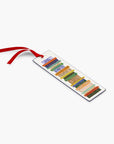 This image displays a Rifle Paper Co. bookmark featuring a stack of colorful, illustrated book spines, complete with a red ribbon affixed to a white background.