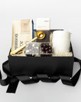 Gift basket with coffee bag and coffee chocolate and caramels, coffee scoop and travel mug with black ribbon on a white background