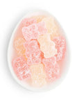Several bubbly bears by Sugarfina are featured in a ceramic white dish white, pink, and orange color on a white background.