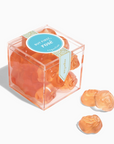 Clear cube-shaped box with rose-shaped candies on a white background