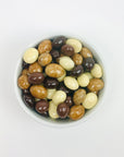 Chocolate covered expresso beans (milk, dark, and white chocolate covering), in a white bowl on a white background.