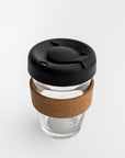 Clear tumbler with cork holder featured transparent tumbler with cork holder and black lid on a white background.