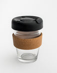 Clear tumbler with cork holder featured transparent tumbler with cork holder and black lid on a white background.
