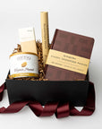Gift basket with a book, bottle, and other items on a white background