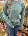 Custom grandma embroidered sweatshirt in green, embroidered in white on the front: Grandma Est. 2024. On the sleeve, Elsie and Josiah with a heart emoji on a woman in a nature background.
