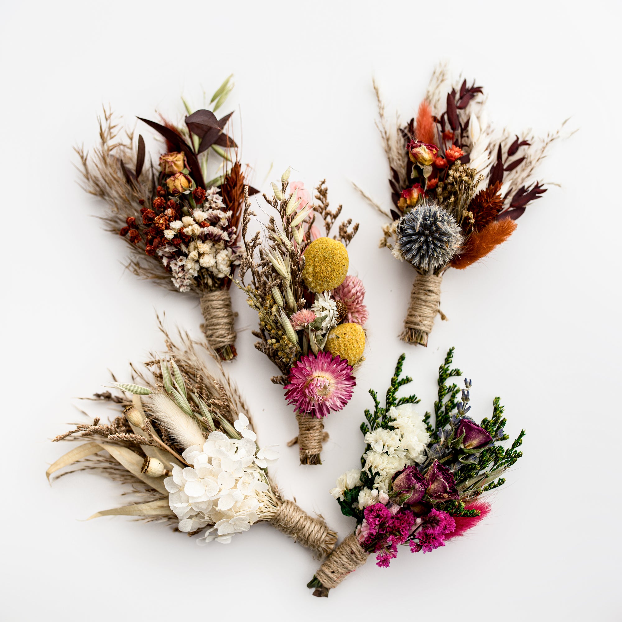 5 dried flower bundles in different colors in a white background.