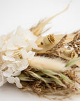close up image of white and green dried floral bundle on white background.
