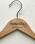 Engraved bride hanger is featured in a natural hanger with silver hook. Engraved Samantha - bridesmaid on a marble-like background.