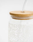 Close-up image of glass straw tumbler with a floral design with the bamboo lid on a white background.