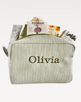Green striped pouch with 'Olivia' embroidered on it, containing various items.