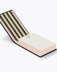 Hawthorne desktop notepad is featured propped open, with the cover slightly raised at an angle to display its striped interior pattern (pink and green) and the notepad's pages in display with a small floral decoration in the upper center, on a white background.