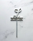 Initial & date wooden cake topper is featured personalized with L and 5.325.24 in silver on a marble like background.