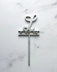 Initial & date wooden cake topper is featured personalized with L and 5.325.24 in silver on a marble like background.