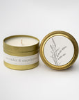 Lavender and eucalyptus travel size candle featured in a gold tin round container with white label black lettering and lid with a white round label with a black silhouette of a lavender flower on a white background.