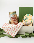 Gift basket with a candle, book, and other items on a white background