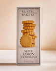 Meyer lemon shortbread cookies are featured in their white box rectangular-shaped box that has the image of the cookies and the information and title in black lettering with black lines border with white background in beige shadow lighting.