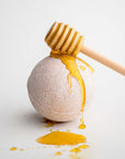 Milk and Honey Bath Bomb featured with honey drizzled on top and dripping, displayed on a white background.