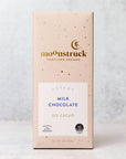 Moonstruck creamy chocolate bar in its rectangular-shaped package that is pink with gold spots, gold lettering, and a white label with blue letters and two symbols in black on a marble-like background.