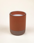Nightcap candle is featured in its amber ceramic jar and brown bottom on a white background.