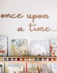 Once upon a time wooden wall cut out is featured in alder wood on top of a children's book in a bookshelf on a white background.