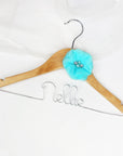 Light wood hanger with silver hook personalized in silver aluminum Nellie with a aqua chiffon flower on a white background.
