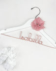 Personalized white flower girl hanger personalized with the name Isabella in rose gold aluminum wire and a pink chiffon flower.
