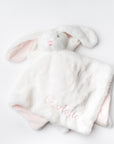 A soft, white, plush bunny security blanket with pink accents and the name "Charlotte" embroidered on it is presented against a bright white backdrop.