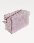 Pink textured toiletry bag with a zipper on a white background