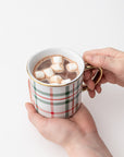 Our signature plaid mug gold rim and handle featured being held with chocolate and marshmallows inside on a white background.