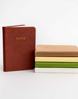 Collection of pocket soft cover notebooks in the different colors they come burgundy, rust, yellow, green and cream.