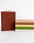 Collection of pocket soft cover notebooks in the different colors they come burgundy, rust, yellow, green and cream.