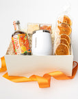 Gift basket with a bottle of cocktail mix, oranges, and a box on a white background