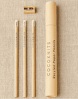 Set of recycled paper pencils with a sharpener and packaging on a textured beige background