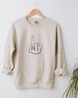 Ring finger engagement sweatshirt featured that has the image in black lines in the middle hanged on a white background with a plant on the right bottom corner.