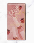 Ritual the Apres Chocolate, wrapped in a pink wrap with raspberries and sparkling wine background image. The label in gold lettering.