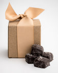 Dark chocolate sea salt caramels are featured in the front, with four pieces displayed, and behind them, the light brown cardstock gift box they come in, wrapped with an oatmeal-colored ribbon.