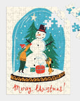 Snow globe mini puzzle is featured almost completely done showing a snow globe illustration with merry Christmas in red on the bottom with some pieces not assembled in the puzzle on the right corner on a grayish background.
