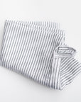 Stripped linen kitchen towel featured in its white and blackl lines design on a white background.