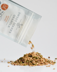 Sweet Dianes granola being poured from a packaging bag onto a white surface.