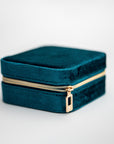 Teal velvet jewelry box, image presents a close-up shot of a rectangular, teal velvet jewelry box with a gold-toned zipper.