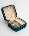 Teal velvet jewelry box, close-up photograph showcases an teal velvet jewelry box, opened to display its beige interior compartments and organizers, set against a clean white backdrop.