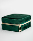 Emerald velvet jewelry box, image presents a close-up shot of a rectangular, emerald-green velvet jewelry box with a gold-toned zipper.