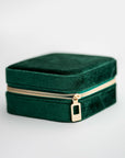 Emerald velvet jewelry box, image presents a close-up shot of a rectangular, emerald-green velvet jewelry box with a gold-toned zipper.