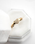 Close up of hite velvet ring box with a gold heart-shaped ring with diamonds and brown gemstones on a white background.