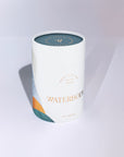 A white cylindrical bath bomb tin labeled WATERBODY Deep Blue Sea Bath Luxe, featuring a teal lid and abstract blue and orange geometric accents on the lower left, set against a clean white background with a soft shadow.